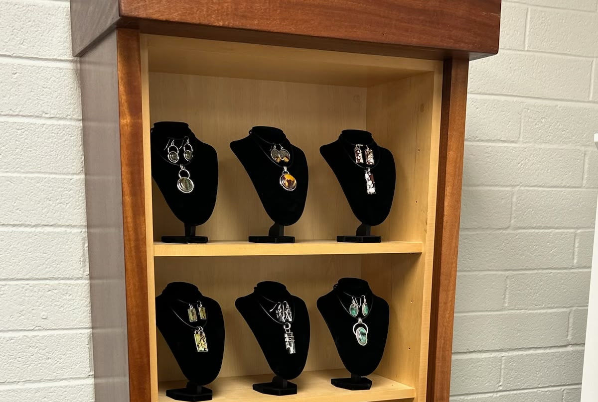 Two shelves of the studio case, six black velvet busts, each holding a stone pendant with the earrings cut to match it.