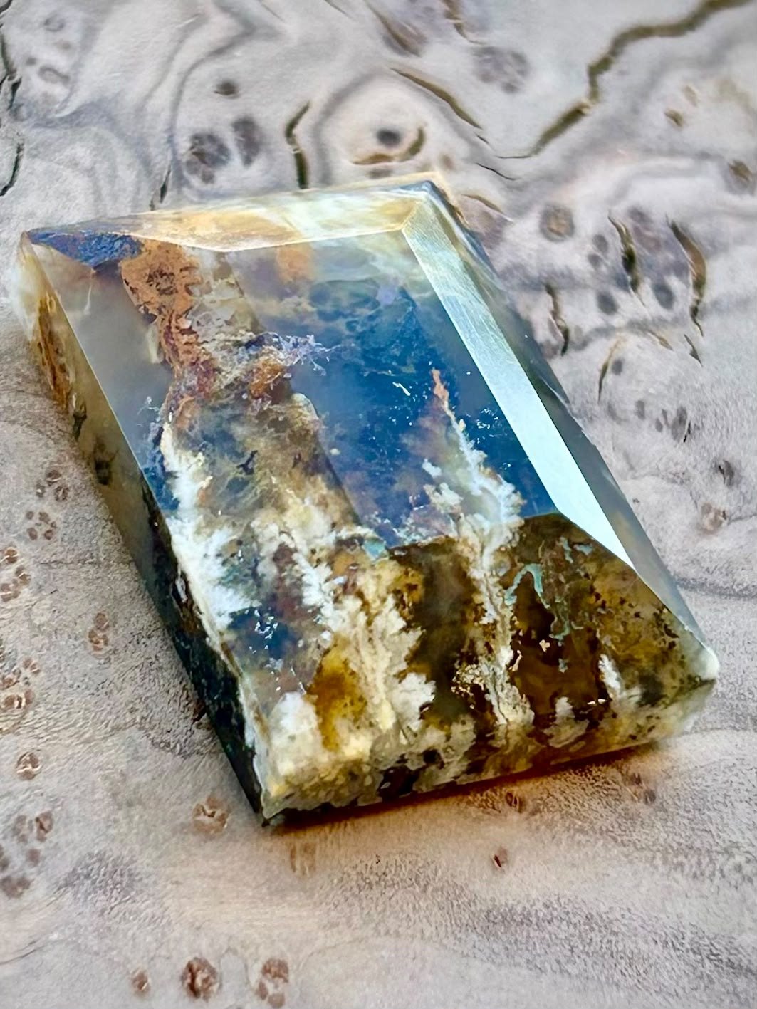 A step cut agate with ochre and white plumes standing in clear blue grey chalcedony.
